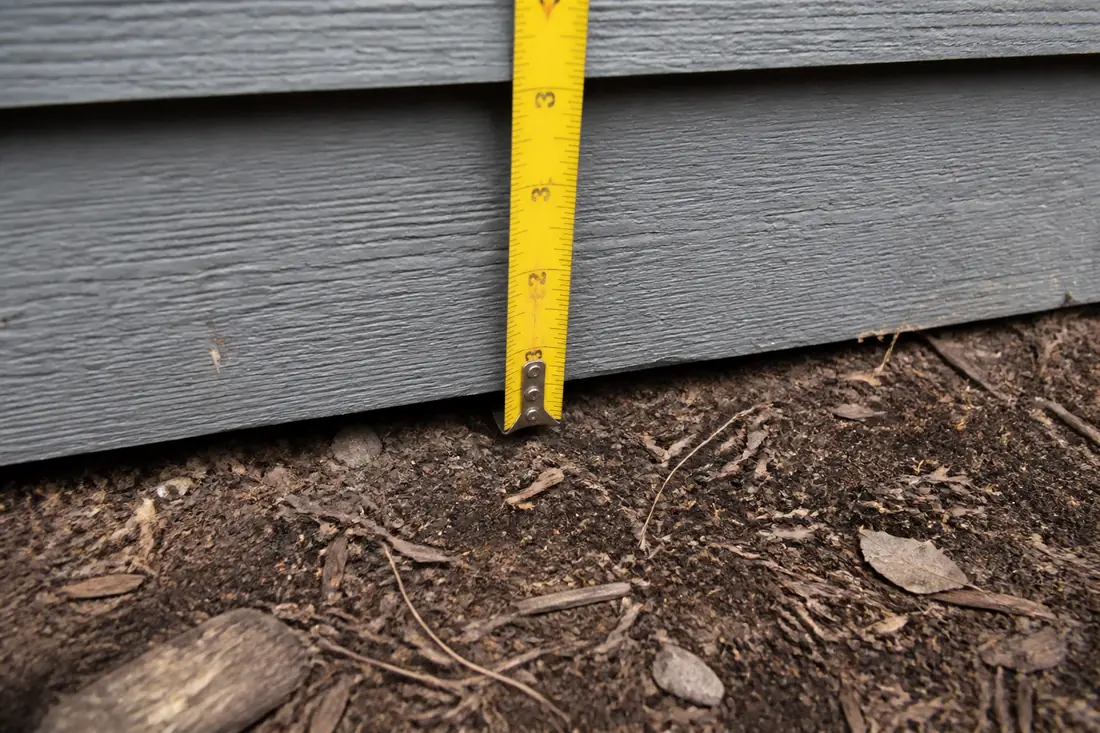 Wood siding running down close to the soil at the base of a wall