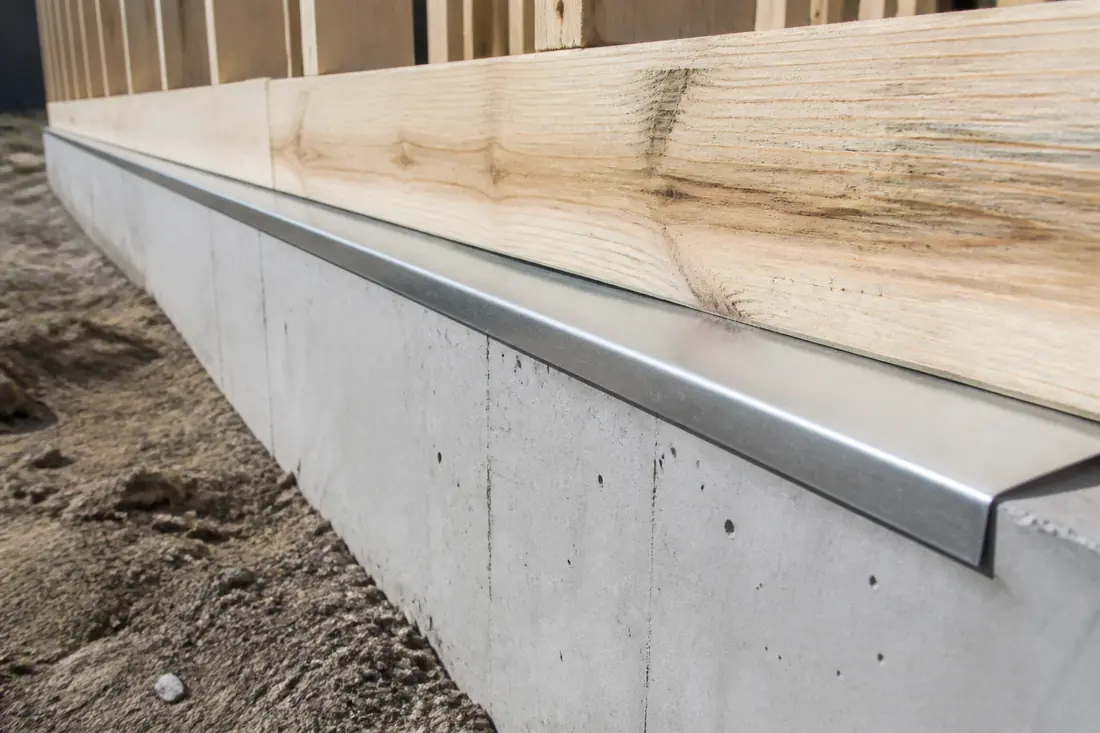 A metal termite shield running along the top of a foundation wall