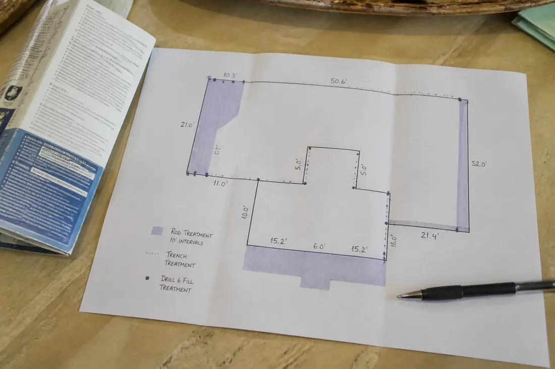 A printed termite treatment diagram showing a house footprint with perimeter dimensions and shaded treatment areas