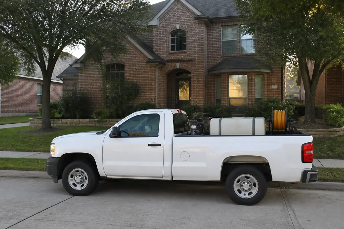 A pest control service truck parked at the curb of a suburban North Texas house